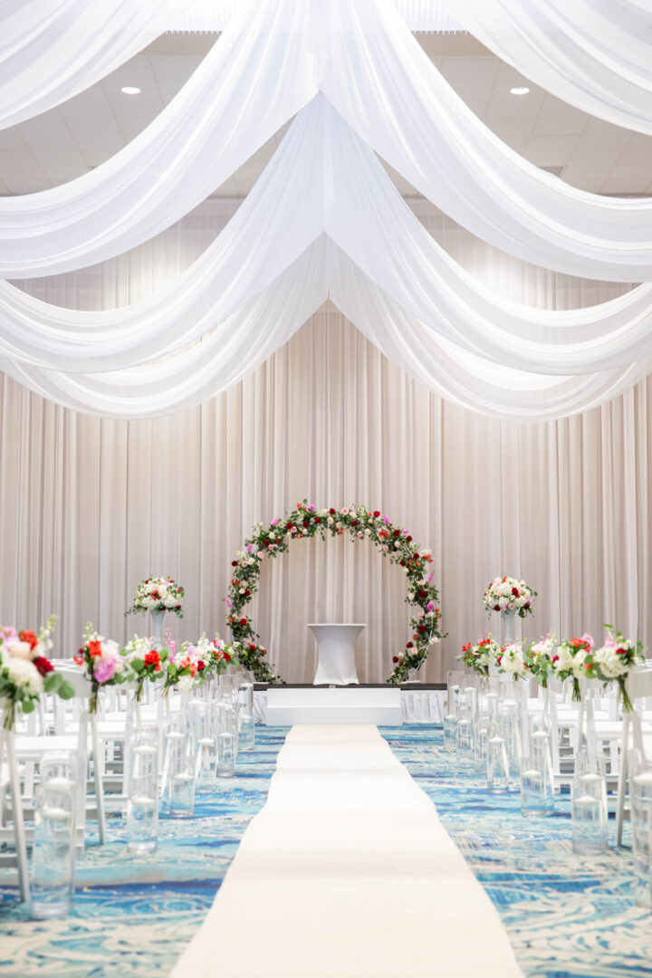 A wedding ceremony with white drapes and flowers.