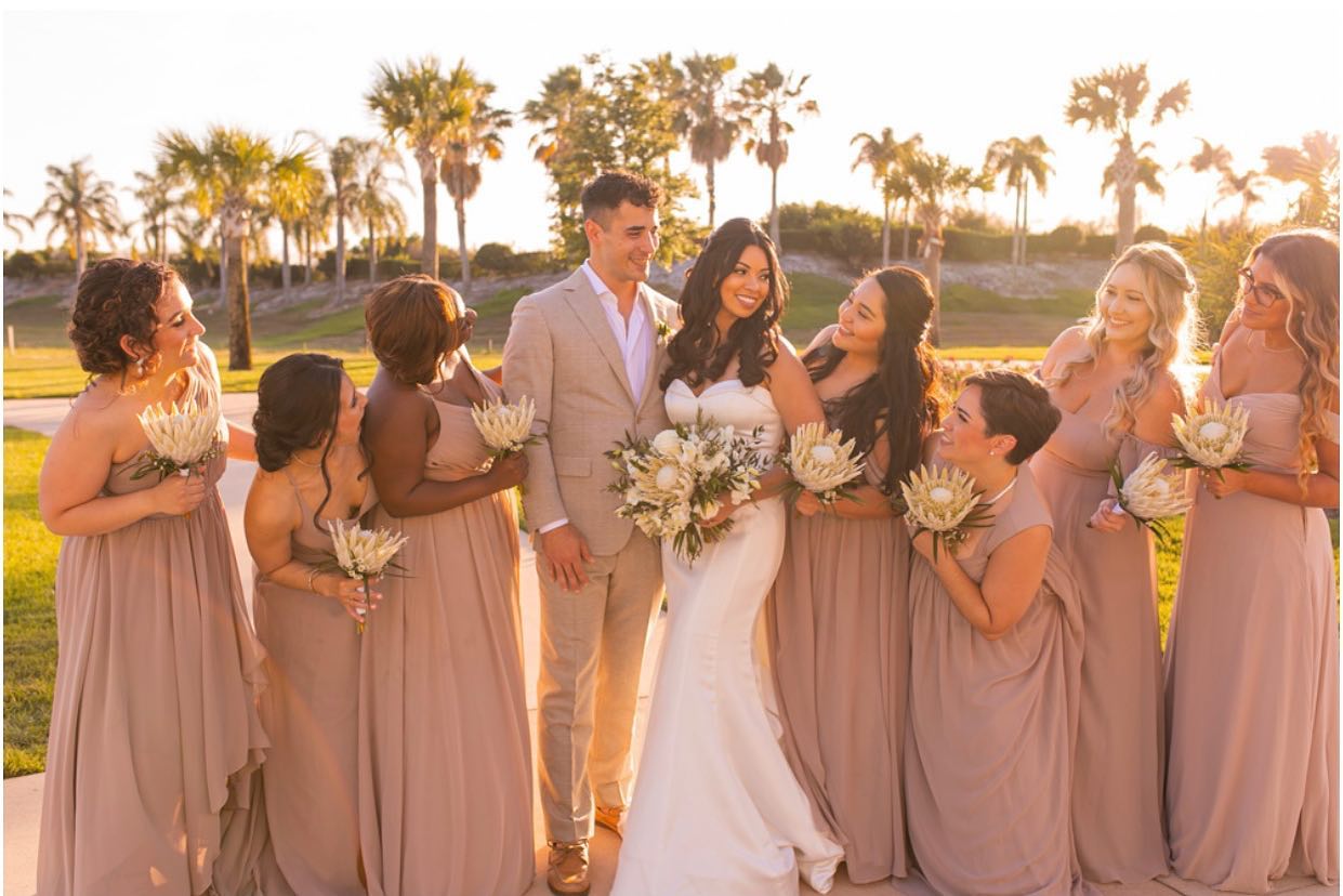 A Bride and Groom Standing With Bridesmaids in Sunset