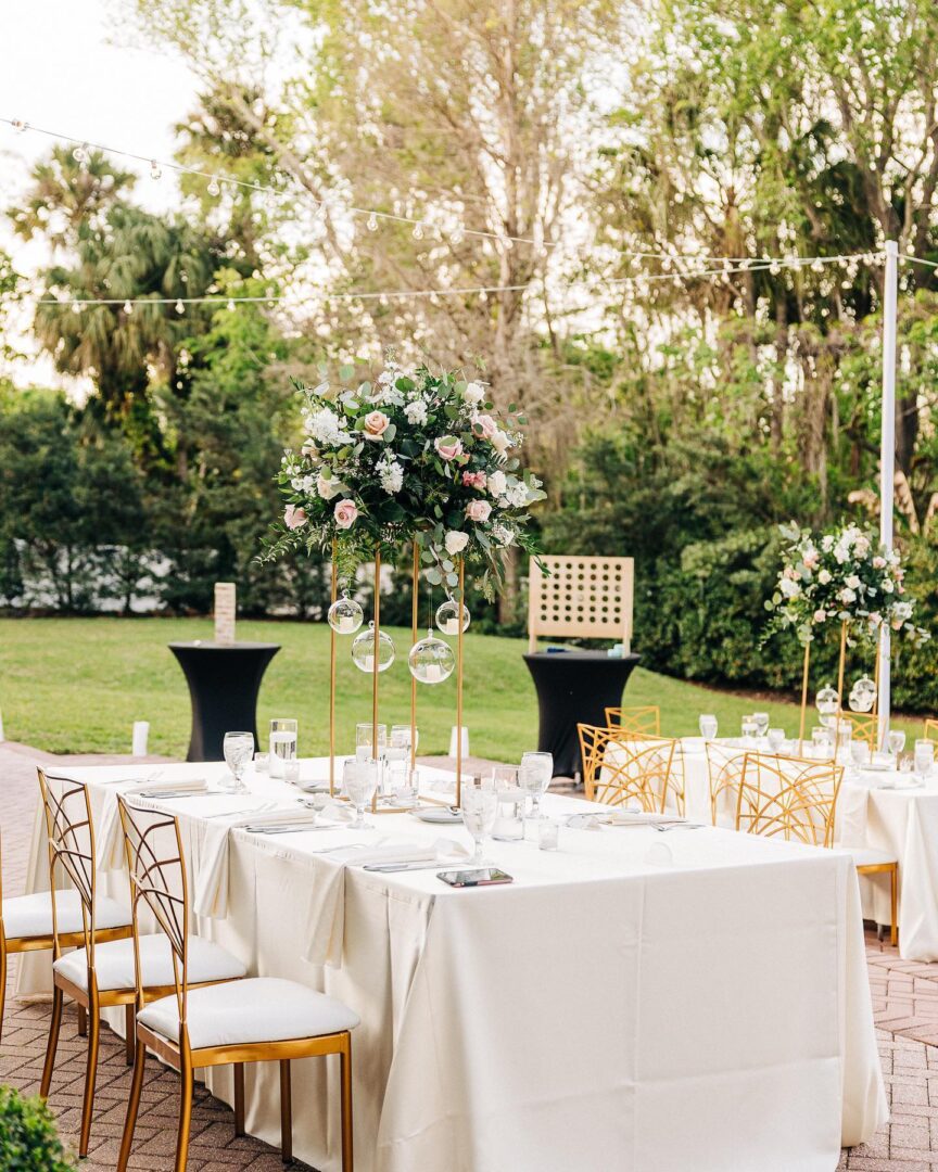 A table set up with white linens and gold chairs.