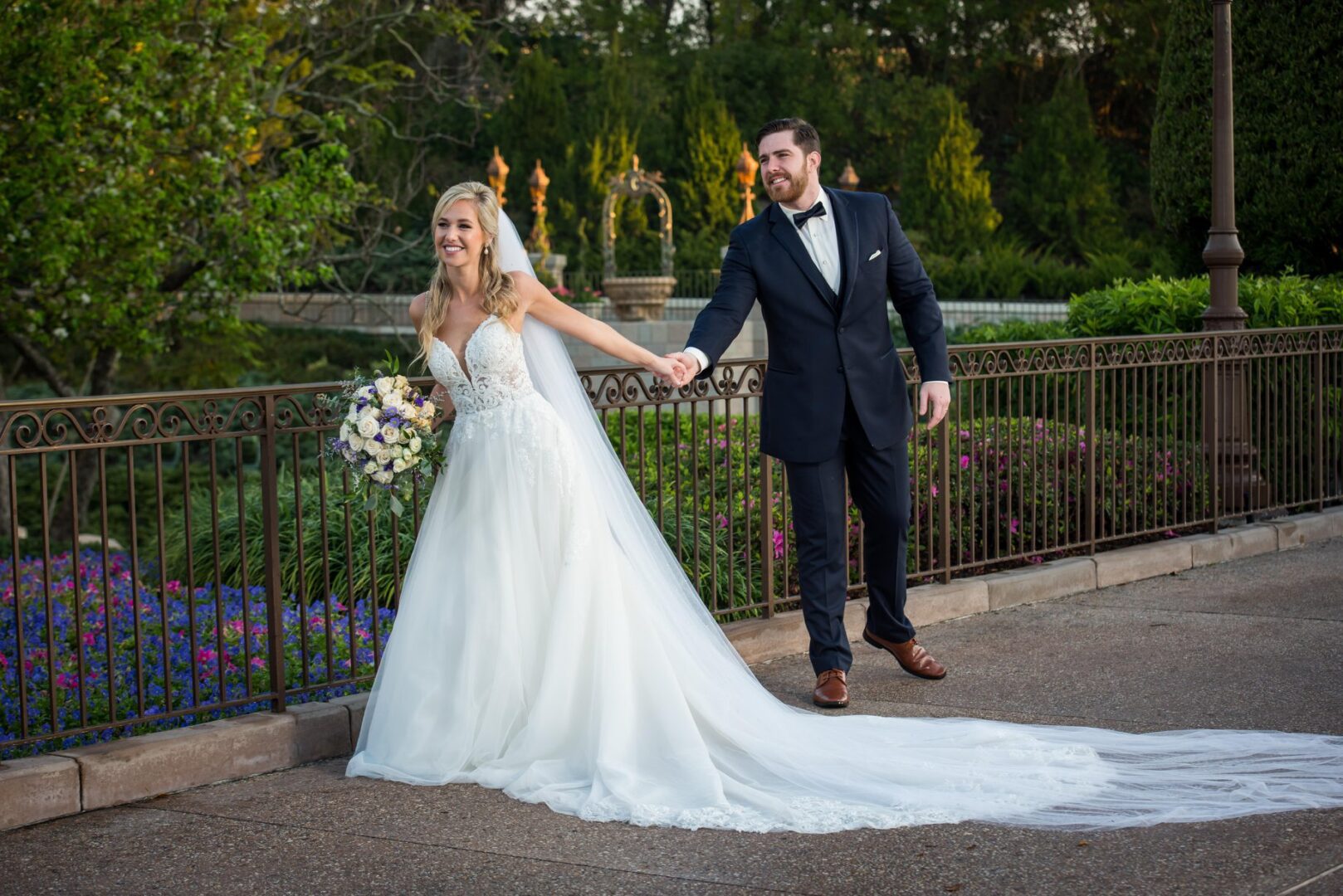 A bride and groom holding hands in front of a fence.