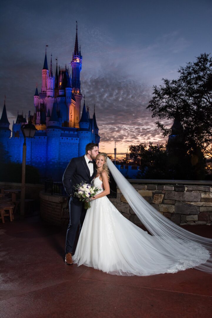 A bride and groom kissing in front of the castle.