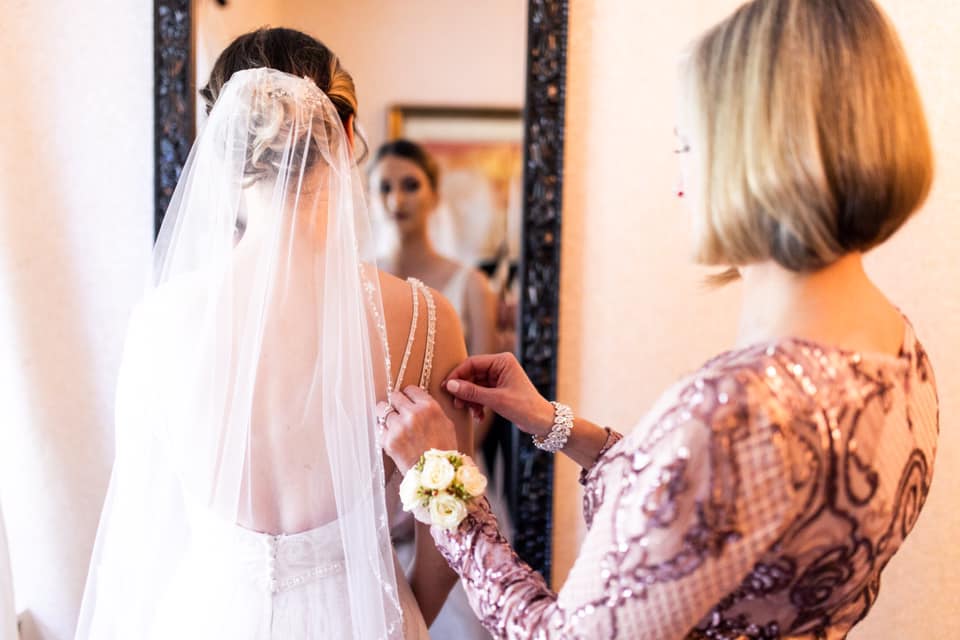 A Bride Getting Dress in Front of a Mirror