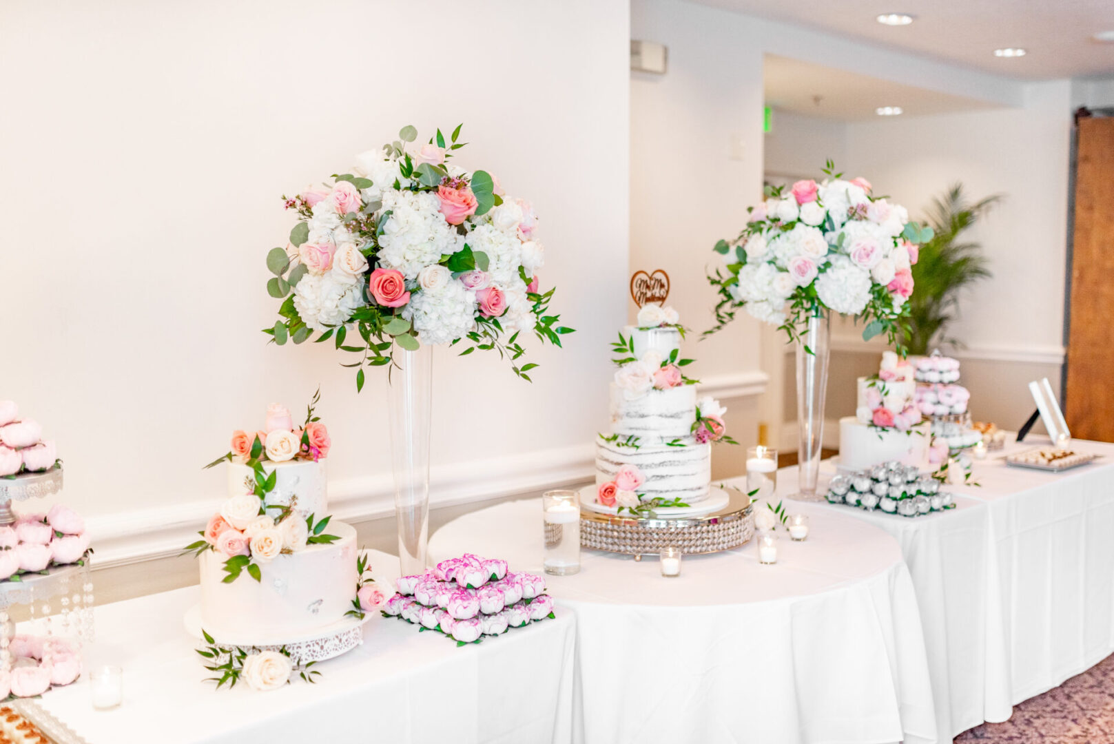 A table with several cakes and flowers on it.