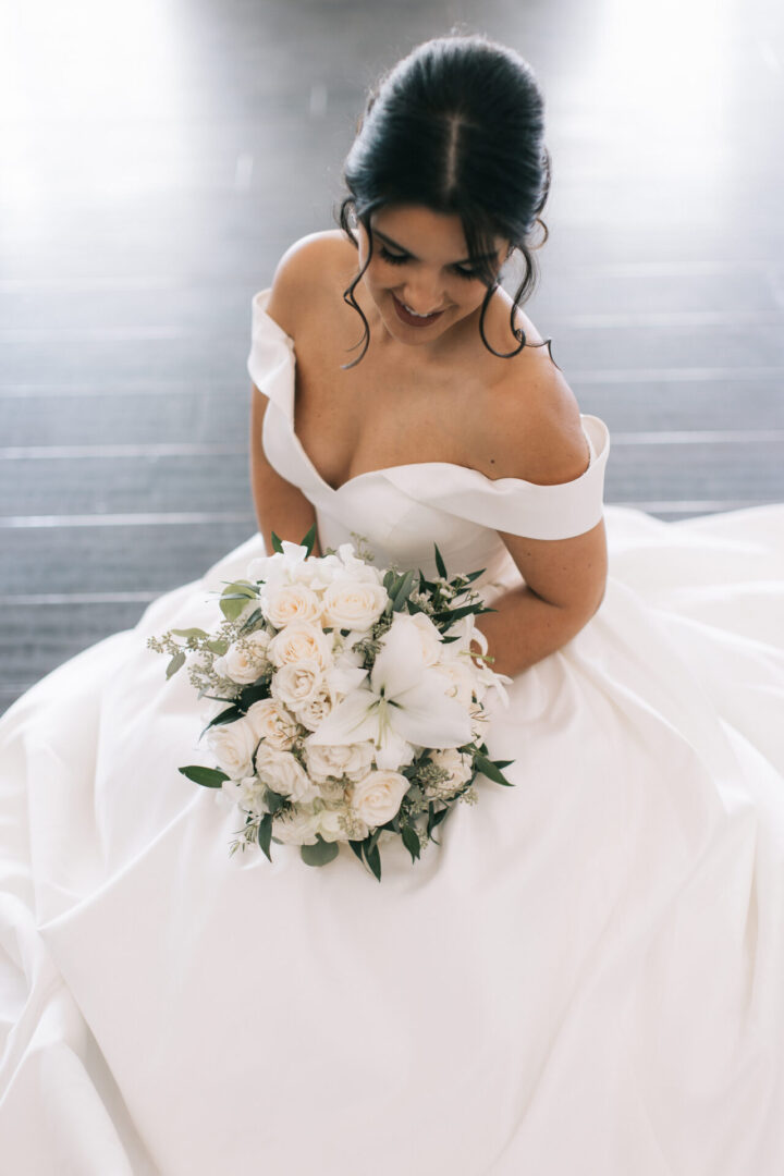 A bride in a white dress holding her bouquet.